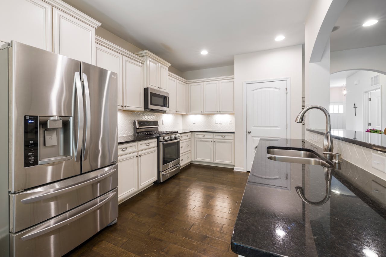 Bright modern kitchen with stainless steel appliances, granite countertops, and wooden flooring.